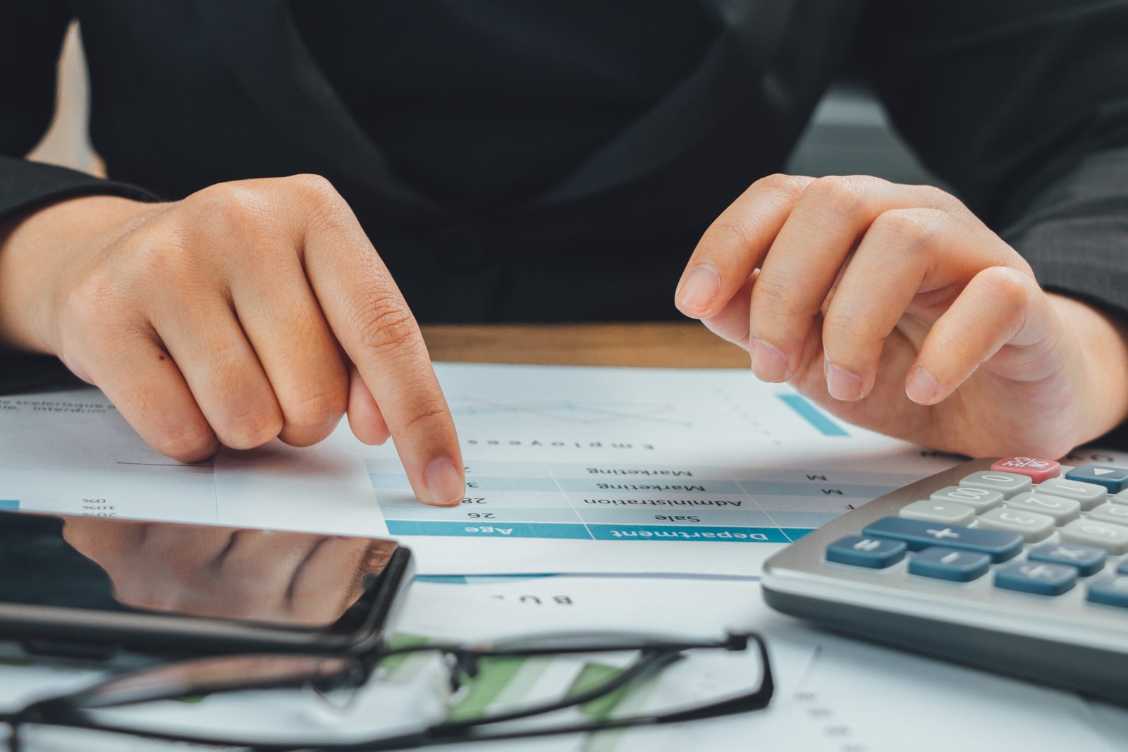 Close up hand of  accountant checking data on document and using calculator, business finance calculation concept